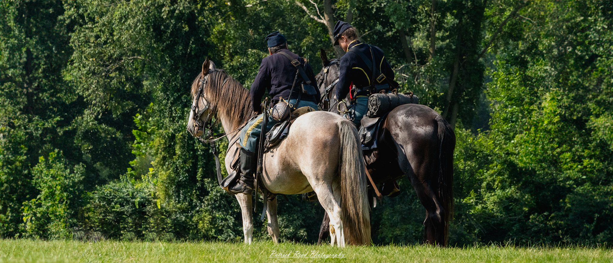 Two cavalry soldiers on horseback, positioned side by side as they prepare for action. Dressed in traditional military uniforms, they exude camaraderie and readiness, showcasing the teamwork and bravery characteristic of cavalry units during their maneuvers.
